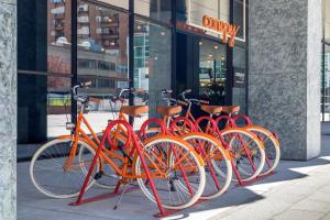 eine Reihe orangefarbener Fahrräder, die vor einem Geschäft geparkt sind in der Unterkunft Canopy by Hilton Madrid Castellana in Madrid