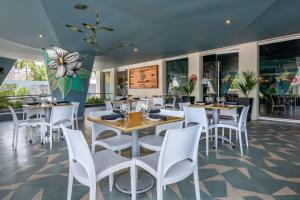 a restaurant with white chairs and tables and windows at Condado Palm Inn San Juan, Tapestry Collection by Hilton in San Juan