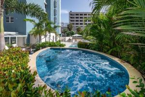 ein großer blauer Pool mit Palmen und Gebäuden in der Unterkunft Condado Palm Inn San Juan, Tapestry Collection by Hilton in San Juan