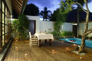 a dining table and chairs on a deck next to a pool at Nunia Boutique Villa in Seminyak