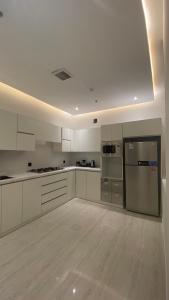 una cocina con armarios blancos y electrodomésticos de acero inoxidable en Luxury Apartment, en Riad