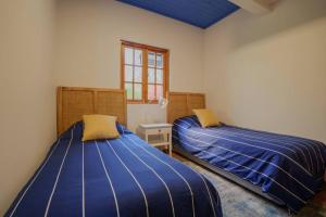 2 camas en una habitación con sábanas azules y ventana en Casa de Lujo frente al Mar en Buchupureo-Curanipe, en Curanipe