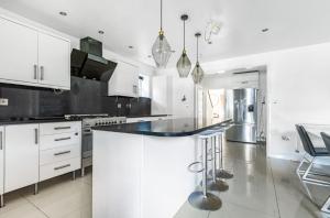 a kitchen with white cabinets and a black counter top at HARTFORDE HOUSE in Borehamwood