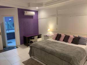 a bedroom with a large bed and a purple wall at Hotel The Green Ecologic in Guarujá