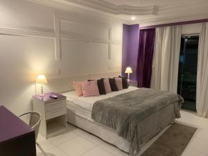 a bedroom with a large bed with a purple wall at Hotel The Green Ecologic in Guarujá