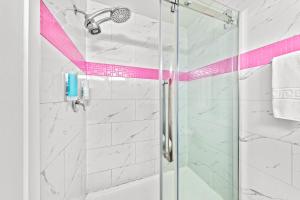 a bathroom with a glass shower with pink accents at The Vista Inn in Kamloops +29 photos