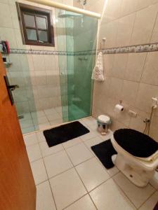 uma casa de banho com um chuveiro e um WC com tapetes em Casa de campo Bela Vista em Itamonte