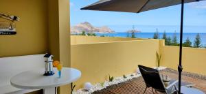 een tafel en stoelen op een balkon met uitzicht op de oceaan bij Thelighthouse Porto Santo in Porto Santo