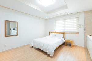 済州市にあるOcean Palade Hotelの白いベッドルーム(ベッド1台、鏡付)