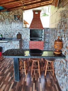a kitchen with a counter with stools and a brick oven at Chácara Nefer Akhet in Domingos Martins