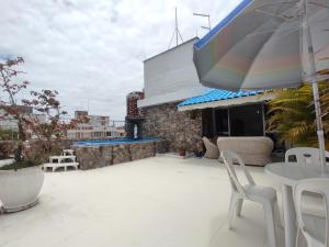 a patio with a table and chairs and an umbrella at Cobertura Enseada Guarujá - 250 metros da praia in Guarujá