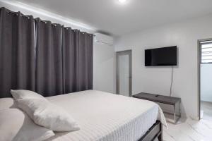 um quarto branco com uma cama e uma televisão em Ramey Cir D, near airport, beaches W/KING Bed. em Aguadilla