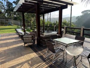 un patio con mesa y sillas en una terraza en Mega Casa em sítio churrasco piscina em Ipiabas RJ, en Barra do Piraí