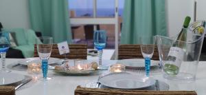 a white table with glasses and plates and candles at Thelighthouse Porto Santo in Porto Santo