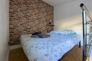 1 dormitorio con 1 cama con pared de ladrillo en Le mini loft - studio - Tain l'Hermitage en Tain-lʼHermitage