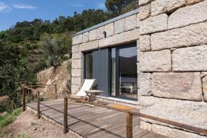uma casa de pedra com um deque e uma cadeira em Quinta da Ribeirinha - Douro River em Paços de Gaiolo