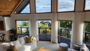 a living room with large windows and a white couch at The Black Chalet in Whitianga