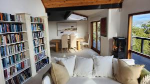 a living room with a couch and shelves of books at The Black Chalet in Whitianga