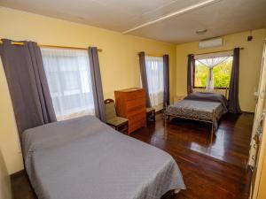 een slaapkamer met 2 bedden, een dressoir en een raam bij Stunning 3-Bed House in Paramaribo Marie's place in Paramaribo
