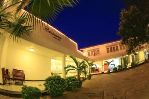 a building with a bench and palm trees at night at Catamaran Beach Hotel in Negombo