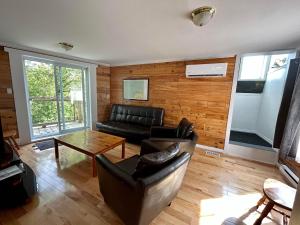 ein Wohnzimmer mit einem Sofa und einem Tisch in der Unterkunft La cachette de la rivière au saumon et spa in Scotstown