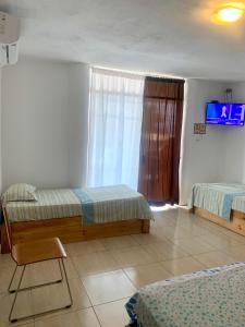 a bedroom with two beds and a tv on the wall at La Tablita in Zorritos