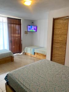 1 dormitorio con 2 camas y TV en la pared en La Tablita en Zorritos