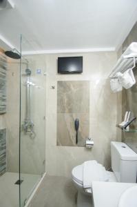 a bathroom with a toilet and a shower with a television at Red Coco Inn de Boracay in Boracay