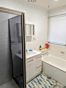 ein Badezimmer mit einer weißen Badewanne, einem Waschbecken und einer Dusche in der Unterkunft Corporate Share House in Melbourne