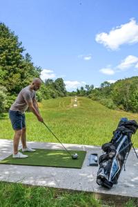 Ein Mann schlägt einen Golfball auf einem Putting Green in der Unterkunft 13-Acre Private Estate, Private Lake, Private Golf Range, Private Forest & Hiking Trails 