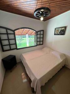niewielka sypialnia z łóżkiem i oknem w obiekcie Lindo sítio para você e sua família! w mieście Guararema