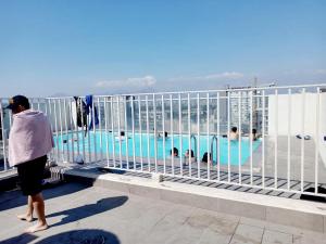 a woman standing on a balcony looking at a pool at Lindo Departamento Amoblado (Cercano a terminal Sur y Aeropuerto) in Santiago