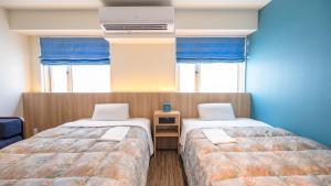 Duas camas num quarto com paredes e janelas azuis em Ise City Hotel em Ise