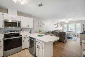 a kitchen with white cabinets and a living room at Barefoot Bungalow in Panama City Beach