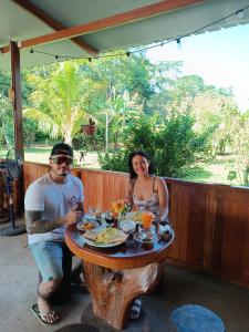 mężczyzna i kobieta siedzący przy drewnianym stole w obiekcie Quirquincho House w mieście Puerto Maldonado
