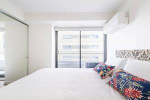 a white bedroom with a large bed and a window at 'The Albert' Where the City meets St Kilda in Melbourne