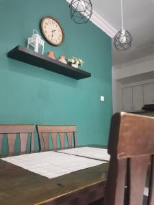 Arfaan Guest House في سكوداي: غرفة طعام مع طاولة وساعة على الحائط