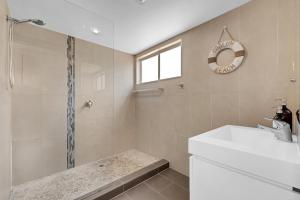 a bathroom with a shower and a sink and a mirror at Surf Dance Apartments in Coolum Beach
