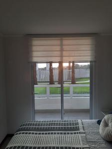 1 dormitorio con ventana y vistas al porche en Acogedor Departamento Central con Piscina, Estacionamiento Privado y Más, en La Serena