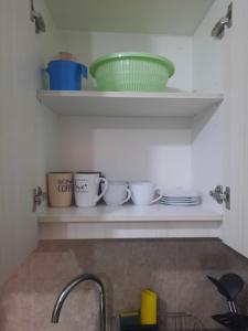 a shelf above a sink with cups and bowls on it at Acogedor Departamento Central con Piscina, Estacionamiento Privado y Más in La Serena