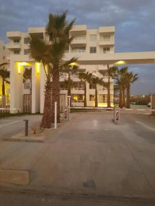 un parcheggio di fronte a un edificio con palme di Acogedor Departamento Central con Piscina, Estacionamiento Privado y Más a La Serena