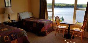 a hotel room with a bed and a table and chairs at St Ann's Motel & Cottage in Baddeck