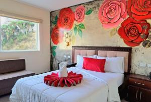 Hotel Loja Bella في لوخا: غرفة نوم مع سرير وورد احمر على الحائط