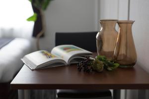einen Tisch mit einem offenen Buch und einer Vase und einem Buch sidx sidx in der Unterkunft Hotel ONE'S RESIDENCE in Sapporo