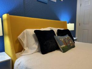 a bed with black and white pillows and a yellow headboard at Luxury Suite by Tampa Convention Center & Hospital in Tampa