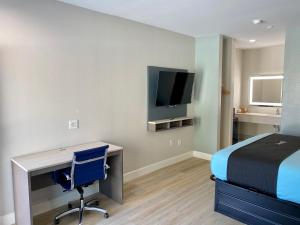 um quarto com uma secretária, uma cama e uma televisão em Blue Star Inn em Houston