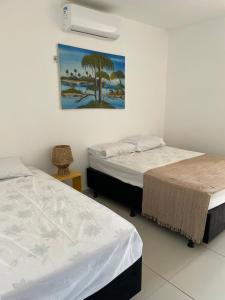 um quarto com duas camas e um quadro na parede em Sunset Chalés em São Miguel do Gostoso