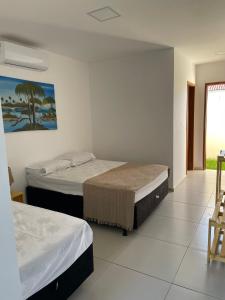 a room with two beds and a table and chairs at Sunset Chalés in São Miguel do Gostoso