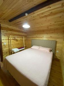 a bedroom with a white bed in a wooden cabin at Doğal,Kaliteli,Huzurlu,Avantajli in Döşeme
