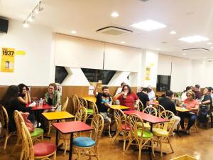 un grupo de personas sentadas en mesas en un restaurante en Sakura Hotel Hatagaya, en Tokio